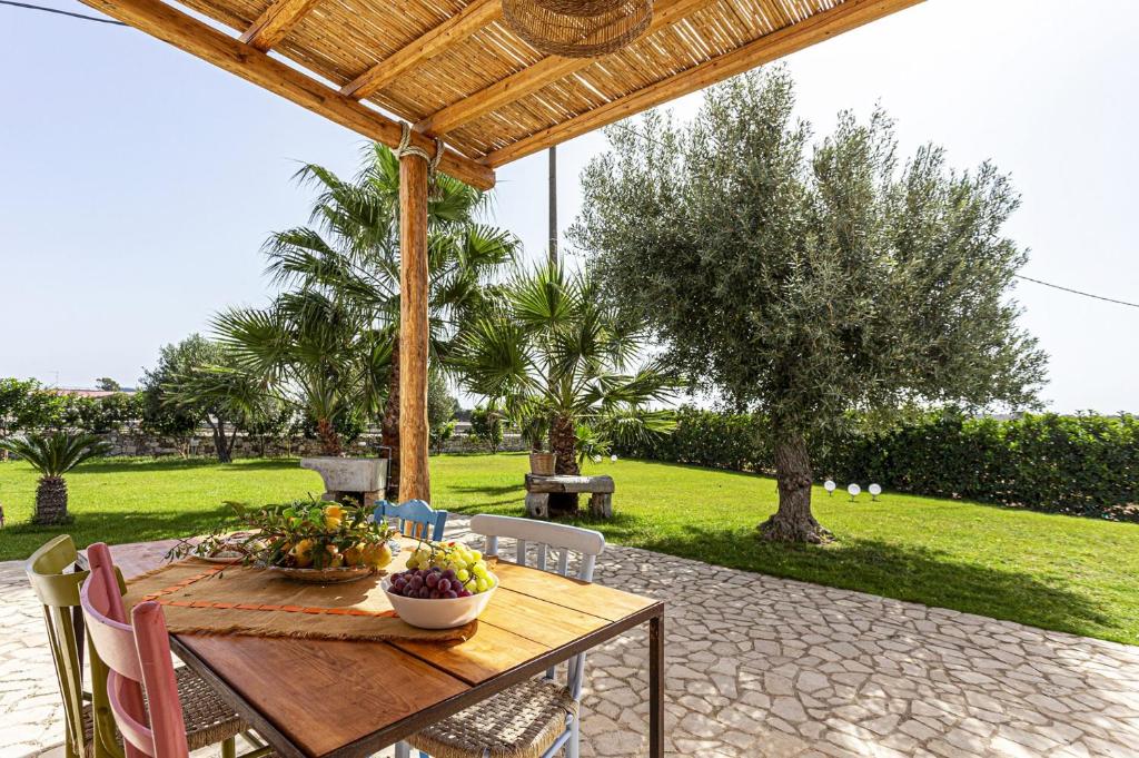 - une table en bois avec un bol de fruits sur la terrasse dans l'établissement Villa Ginevra by Villa Plus, à Ispica
