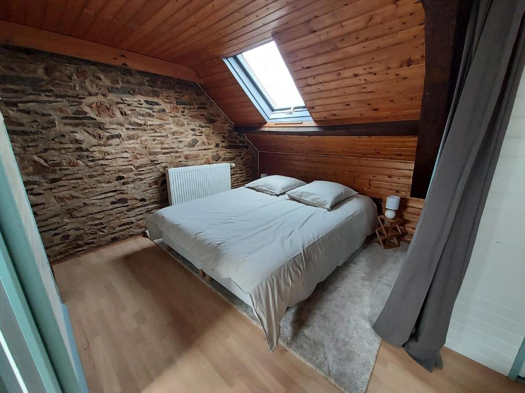 une chambre avec un lit dans un mur de briques dans l'établissement Gites de la Janais, à Le Pin
