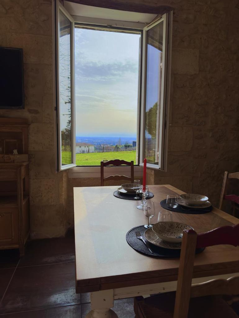- une table avec vue sur l'océan depuis une fenêtre dans l'établissement SPA, Élégance et Charme au Cœur des Vignes - Piscine&SPA Décoration Artisanale, à Le Pian-sur-Garonne