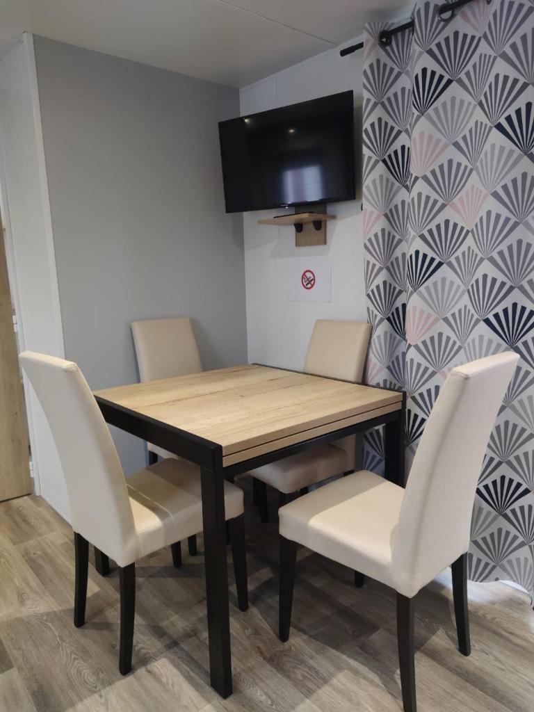 une table à manger avec des chaises blanches et une télévision dans l'établissement Mobil home 3 chambres Accès direct plage 4 Etoiles, à Canet