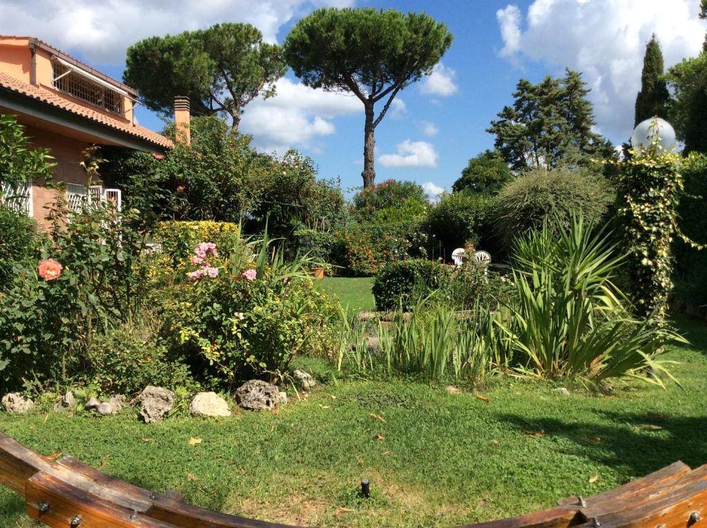 un jardin avec un banc et quelques buissons et arbres dans l'établissement Villa Nanda a 15 minuti da Roma piscina esclusiva , villa nella natura, à Formello