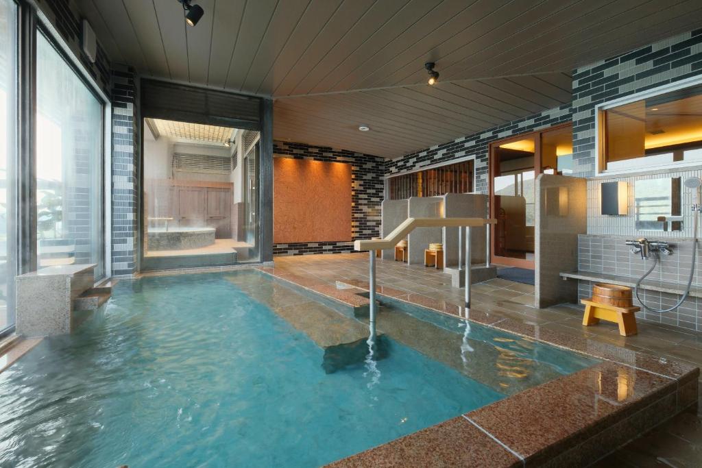 une salle de bain avec une grande piscine d'eau à l'intérieur dans l'établissement Keishokan Sazanamitei, à Fukuyama
