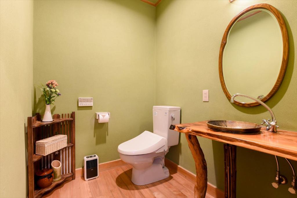 une salle de bain avec toilettes, lavabo et miroir dans l'établissement Hanare Yado Yosizumi, à Itō