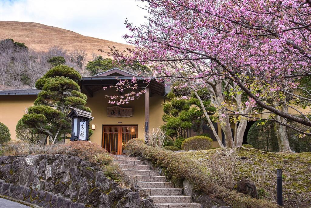 une maison avec un arbre en fleurs devant dans l'établissement Hanare Yado Yosizumi, à Itō