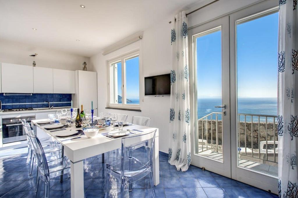 Il dispose d'un balcon et d'une cuisine blanche avec une table et des chaises. dans l'établissement Belvedere delle Sirene with Views Pool and Guest Services by Feeling Italy, à Colli di Fontanelle