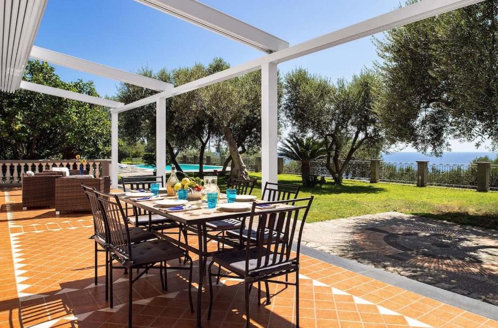 un patio avec une table et des chaises sous une pergola dans l'établissement Relais Mamma Mia Sea Views Pool & Terraces, à Massa Lubrense