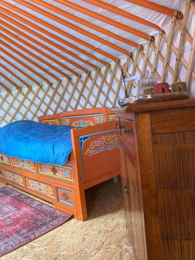 un lit dans une yourte avec une table en bois et un bureau dans l'établissement La Yourte de la Mariotte, à Montredon