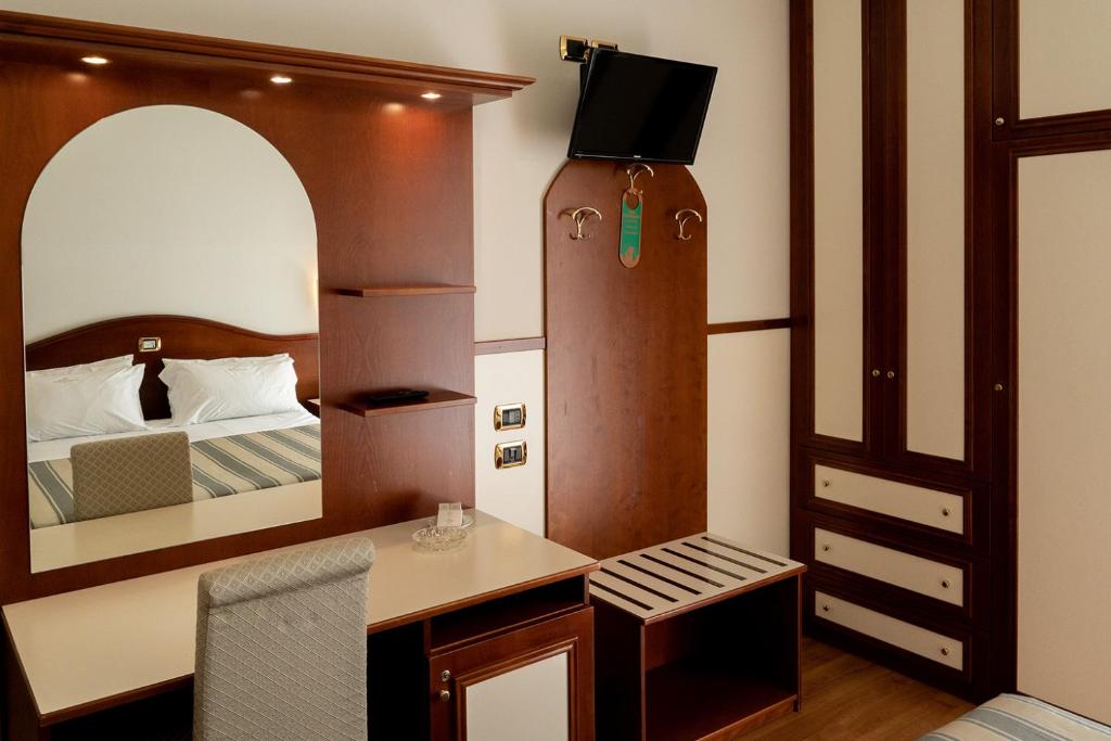 une pièce avec une chambre avec un lit et un miroir dans l'établissement Hotels Vidi Miramare & Delfino, à Lido di Jesolo