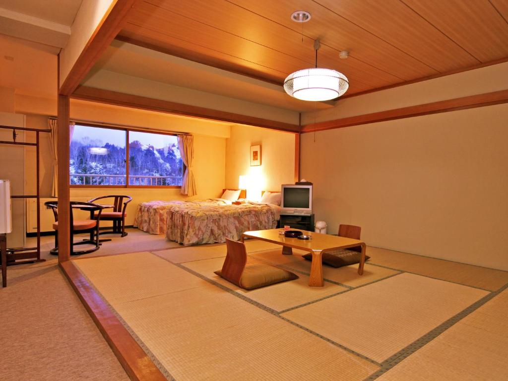 une chambre d'hôtel avec un lit et une table dans l'établissement Kidoike Onsen Hotel, à Yamanouchi