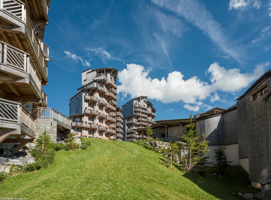 un immeuble d'appartements sur une colline herbeuse entre deux bâtiments dans l'établissement Résidence Pierre & Vacances Premium L'Amara, à Avoriaz 37 autres photos