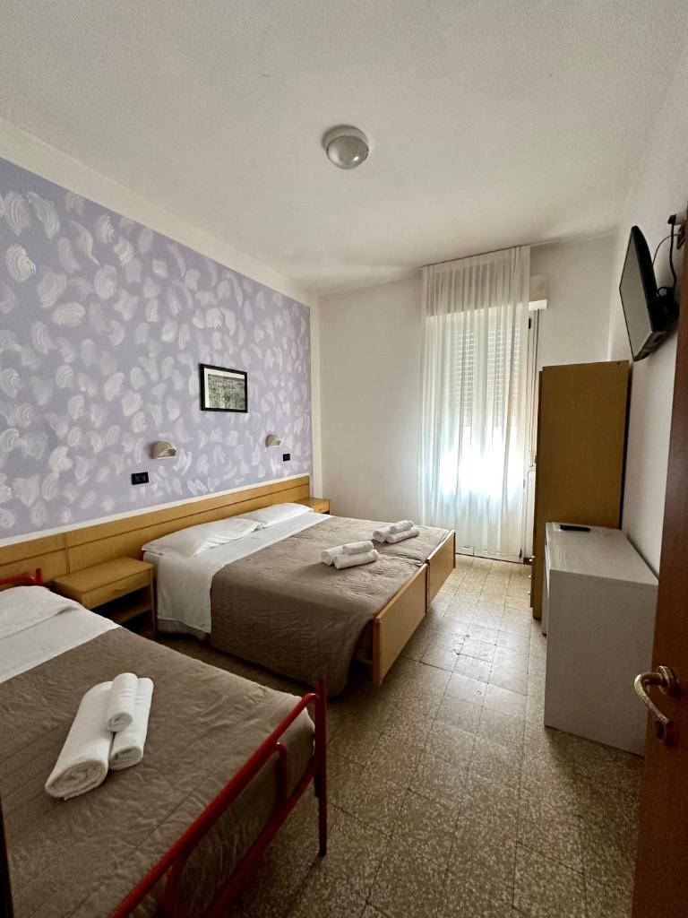 une chambre d'hôtel avec deux lits et une fenêtre dans l'établissement Hotel Enna Rimini, à Rimini
