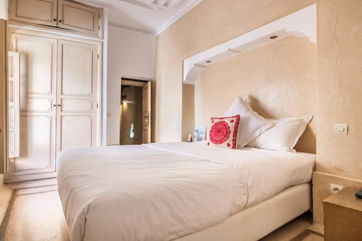 - une chambre avec un grand lit blanc et un oreiller rouge dans l'établissement Riad Dar Ten, à Marrakech