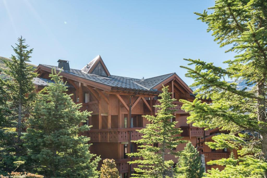 une grande maison en rondins entourée d'arbres dans l'établissement Résidence Pierre & Vacances Premium Les Alpages de Reberty, aux Menuires