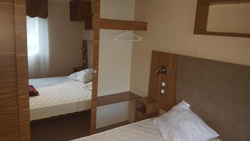 - une petite chambre avec 2 lits et un miroir dans l'établissement Mobil-home 3ch, 2 sdbwc, tout confort camping les allais Trogues, à Trogues