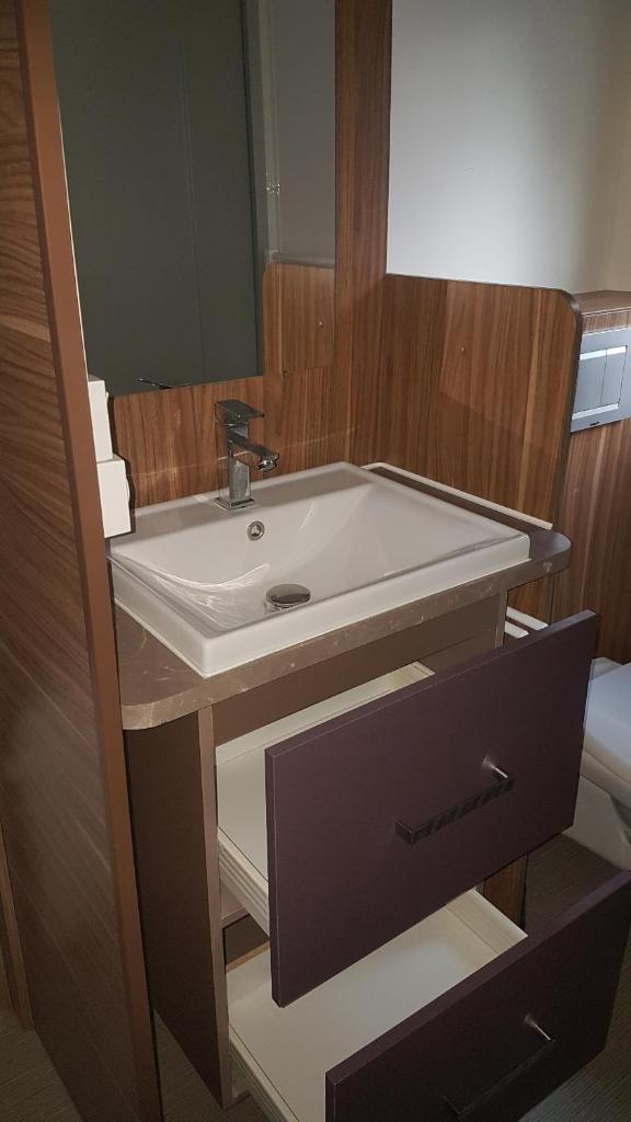 une salle de bain avec un lavabo blanc et un miroir dans l'établissement Mobil-home 3ch, 2 sdbwc, tout confort camping les allais Trogues, à Trogues