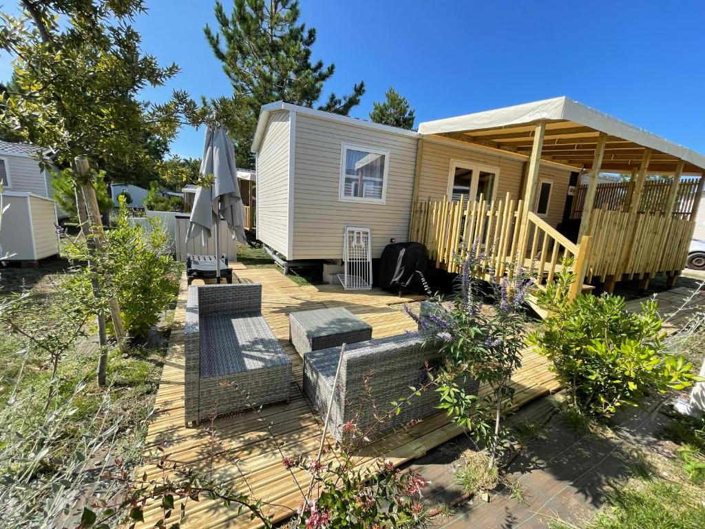 une petite maison avec une terrasse et un hangar dans l'établissement Mobil Home FI11 Camping les Viviers, à Lège-Cap-Ferret