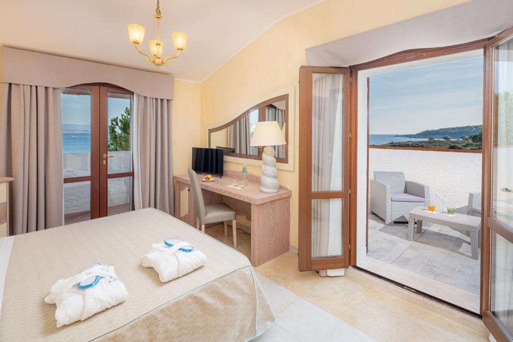une chambre d'hôtel avec un lit et une vue sur l'océan dans l'établissement Hotel Punta Negra, à Alghero
