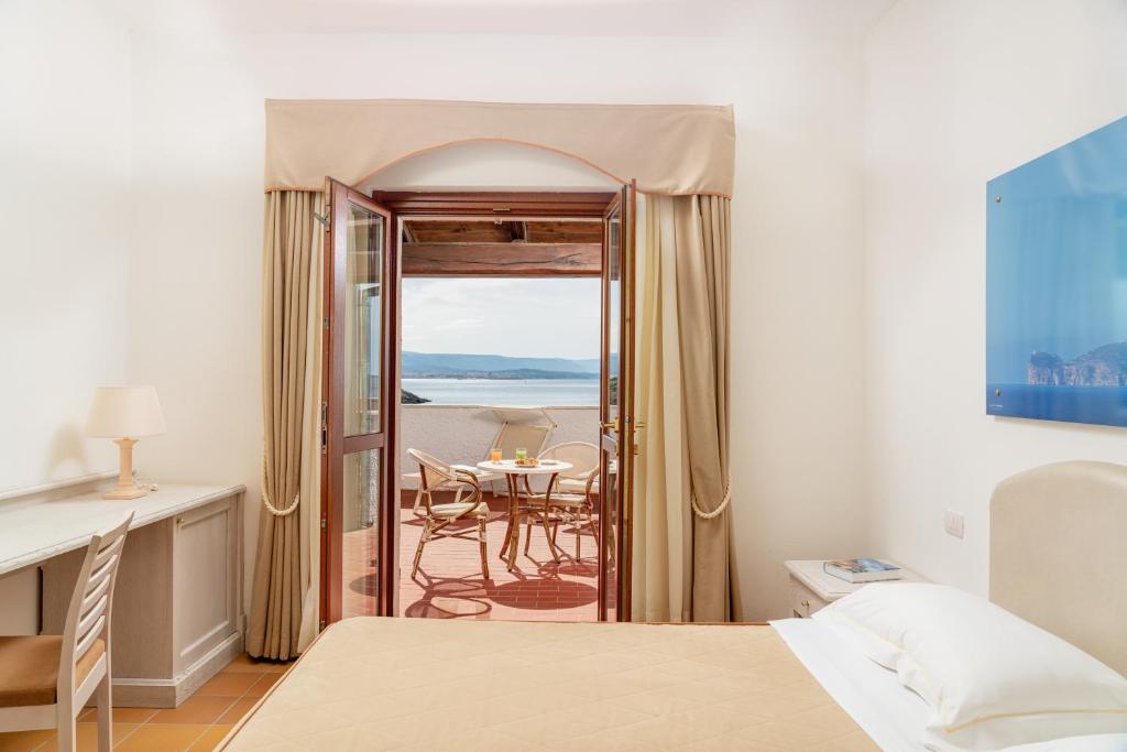 une chambre avec un lit et une table avec vue dans l'établissement Hotel Punta Negra, à Alghero
