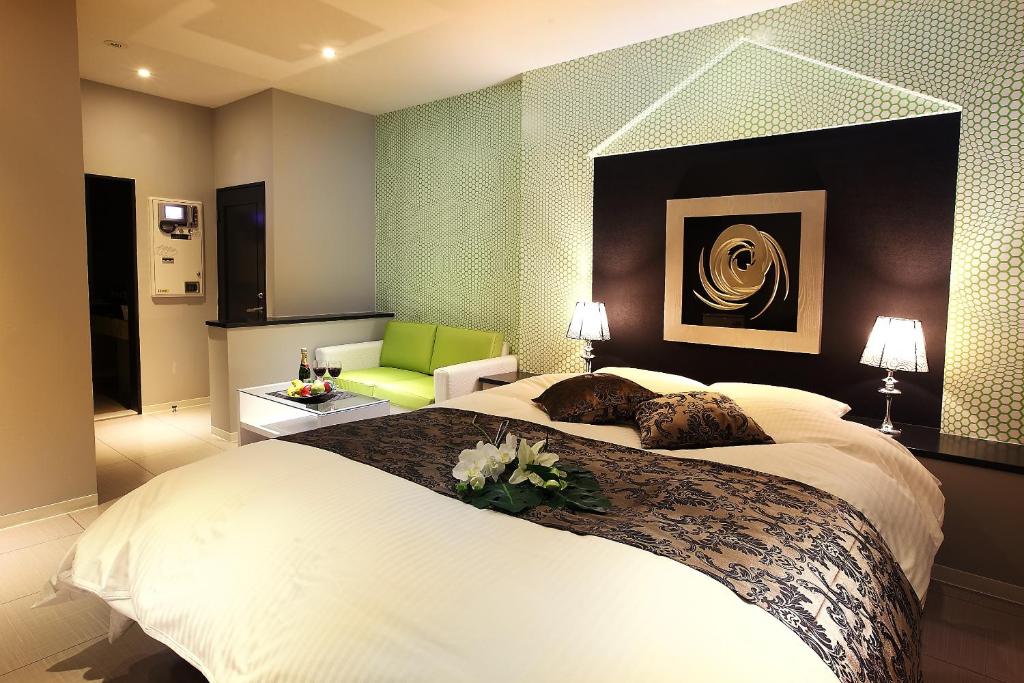 une chambre avec un grand lit et une chaise verte dans l'établissement Hotel L'eclair (Adult Only), à Fukuyama