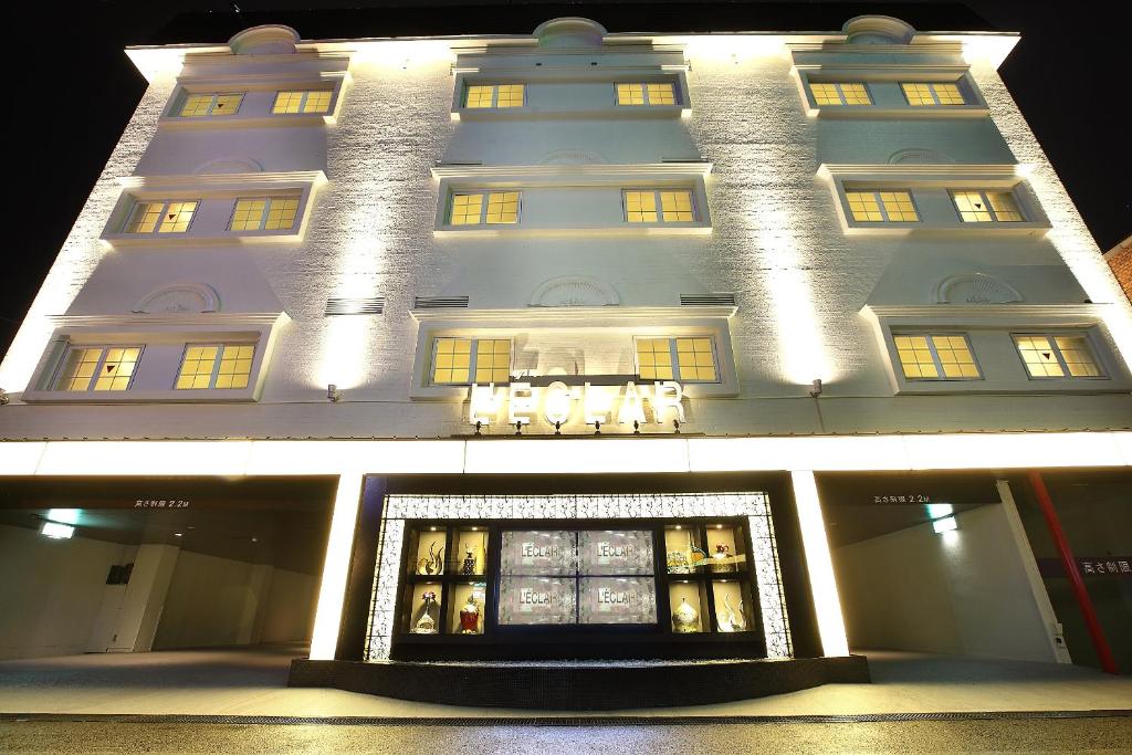 un grand bâtiment blanc avec une façade de magasin la nuit dans l'établissement Hotel L'eclair (Adult Only), à Fukuyama