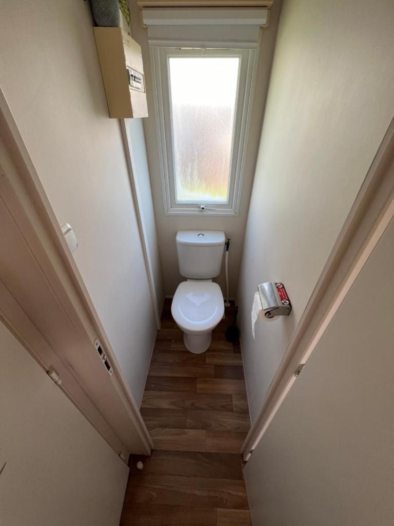 Elle comprend une petite salle de bains pourvue de toilettes et d'une fenêtre. dans l'établissement Mobilhome 3 chambres, à Boofzheim 4 autres photos