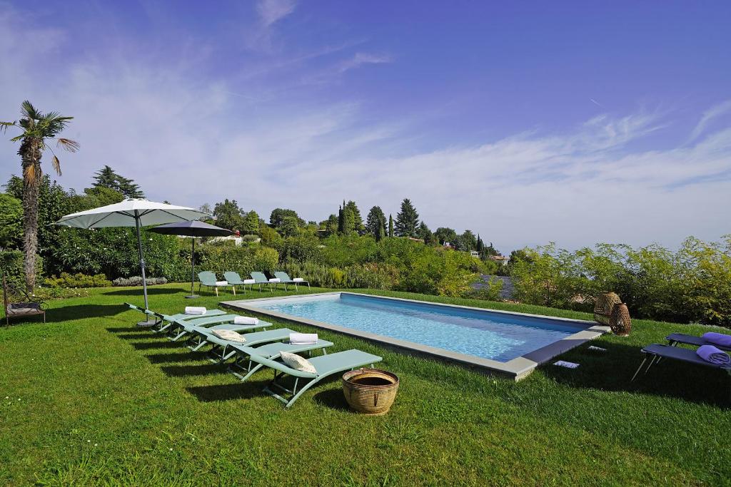 une piscine avec des chaises longues et un parasol dans l'établissement Villa Madeleine, à Padenghe sul Garda