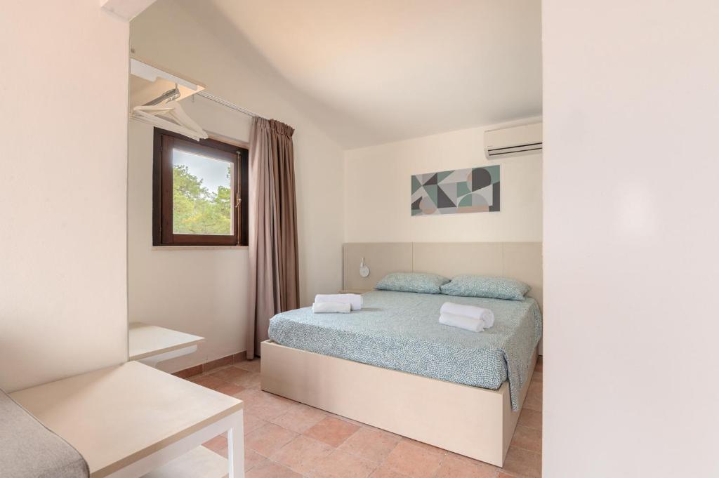 une petite chambre avec un lit et une fenêtre dans l'établissement Q Resort, à Marina di Sorso 64 autres photos