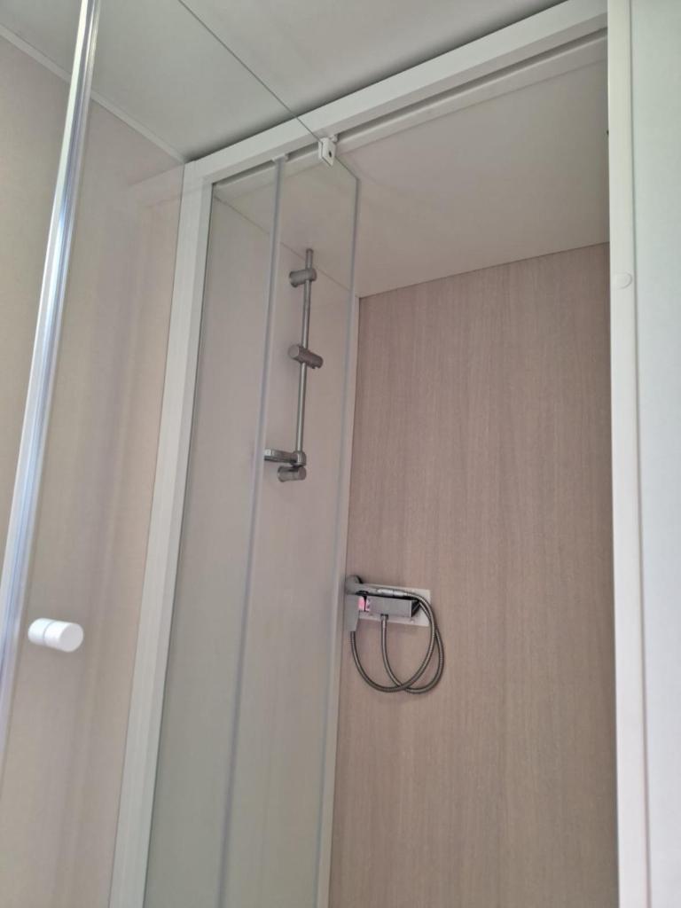 une douche avec une porte vitrée dans une salle de bain dans l'établissement Mobil-home camping Mar Estang, à Canet