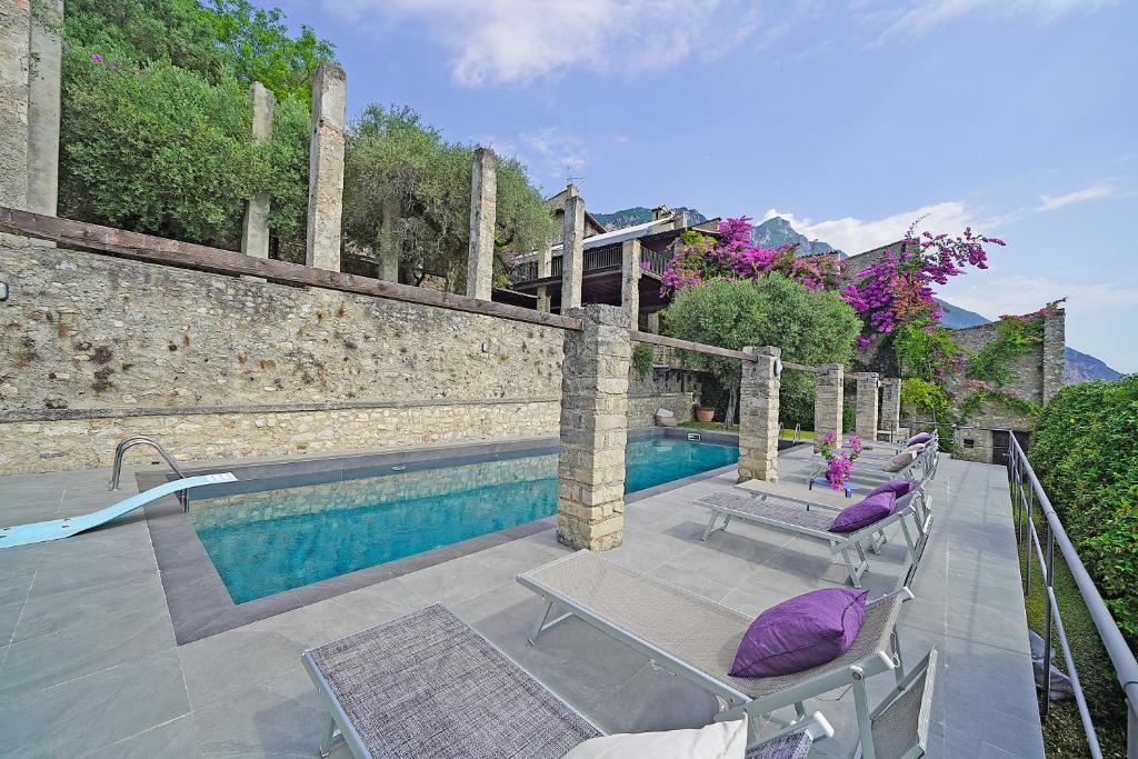 - une piscine avec 2 chaises et un oreiller pourpre dans l'établissement Villa Rachele: stunning luxury villa in centre Gargnano with private pool and breathtaking views, à Gargnano