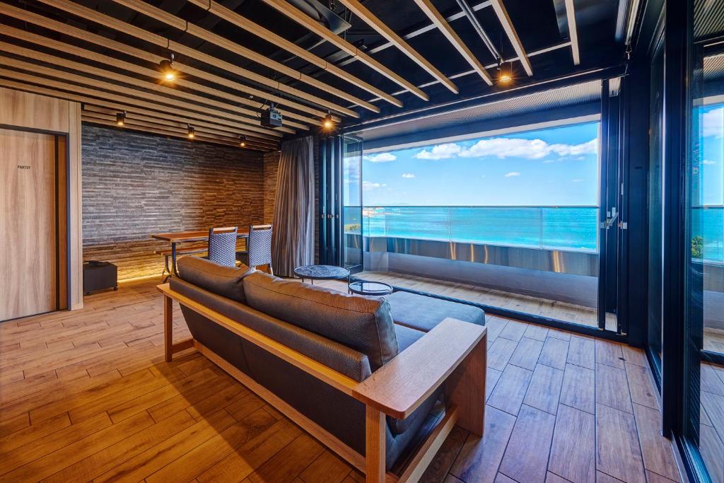 une chambre avec un canapé et une vue sur l'océan dans l'établissement Resort Hills Toyohama Soranokaze, à Toba