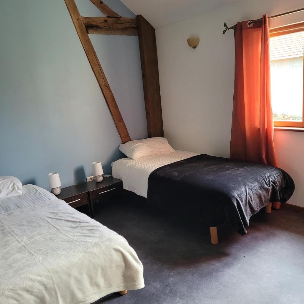 une chambre avec deux lits et une fenêtre dans l'établissement gites le ciel clair, à Mortroux 36 autres photos