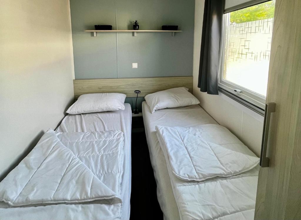 deux lits dans une petite pièce avec une fenêtre dans l'établissement Au Ferret plage,piscines à 2 pas en famille by Vayny, à Lège-Cap-Ferret