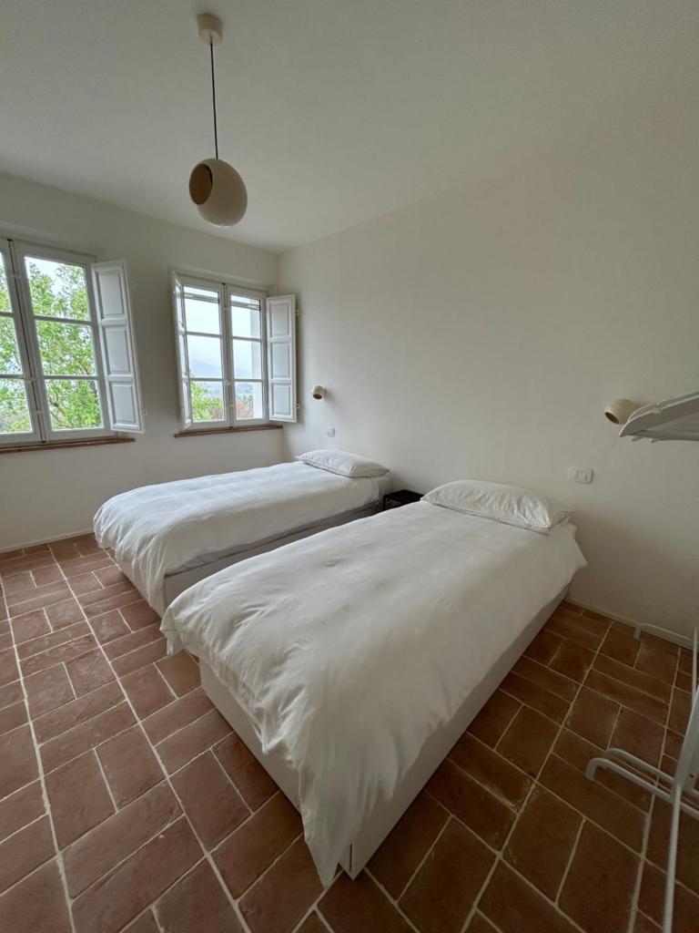 deux lits dans une chambre avec deux fenêtres dans l'établissement Casa Oro, à Montecarlo