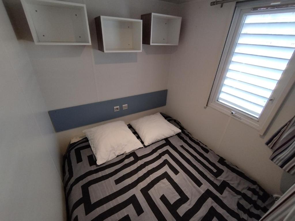 une petite chambre avec un lit et une fenêtre dans l'établissement Mobil home à louer dans camping des cigales le muy 5 étoiles, au Muy