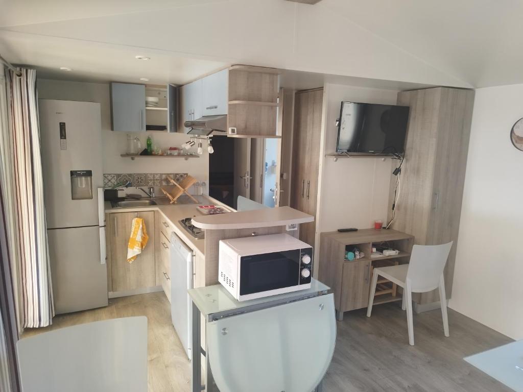 une petite cuisine avec un four micro-ondes sur un comptoir dans l'établissement Mobil home à louer dans camping des cigales le muy 5 étoiles, au Muy