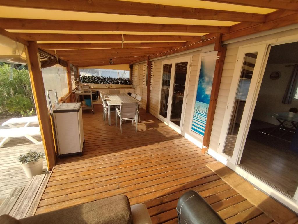 une terrasse en bois avec une table et des chaises dessus dans l'établissement Mobil home à louer dans camping des cigales le muy 5 étoiles, au Muy