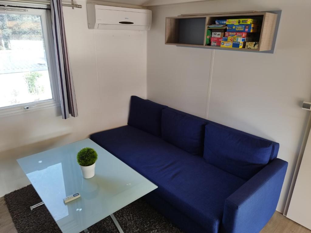 un canapé bleu et une table dans une pièce dans l'établissement Mobil home à louer dans camping des cigales le muy 5 étoiles, au Muy 1 autre photo