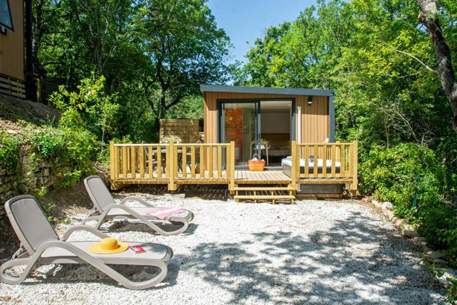 une petite maison avec deux chaises et une terrasse couverte dans l'établissement Camping Le Luberon, à Apt