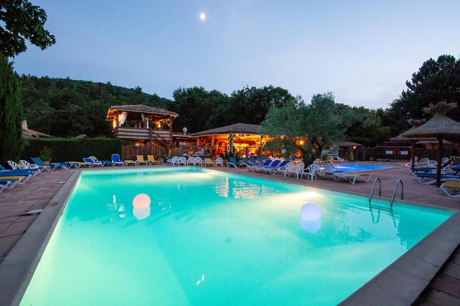 une grande piscine avec une maison en arrière-plan dans l'établissement Camping Le Luberon, à Apt