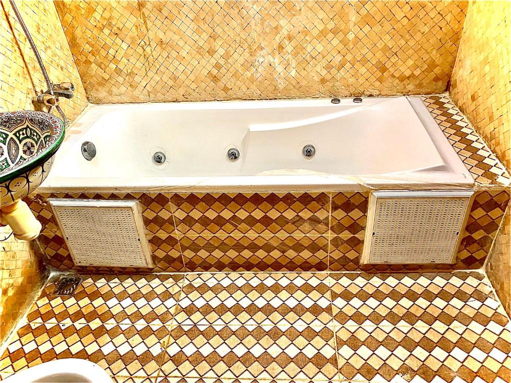 La salle de bains est pourvue d'une baignoire et de carrelage. dans l'établissement Riad Atlas logement entier privé avec jacuzzi au cœur de Marrakesh entire accommodation, à Marrakech