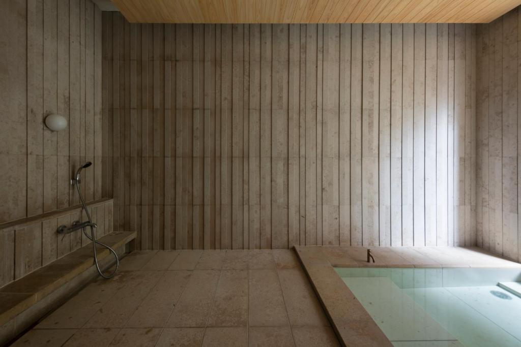 une salle de bains vide avec baignoire et fenêtre dans l'établissement Mikuniya, à Toyooka