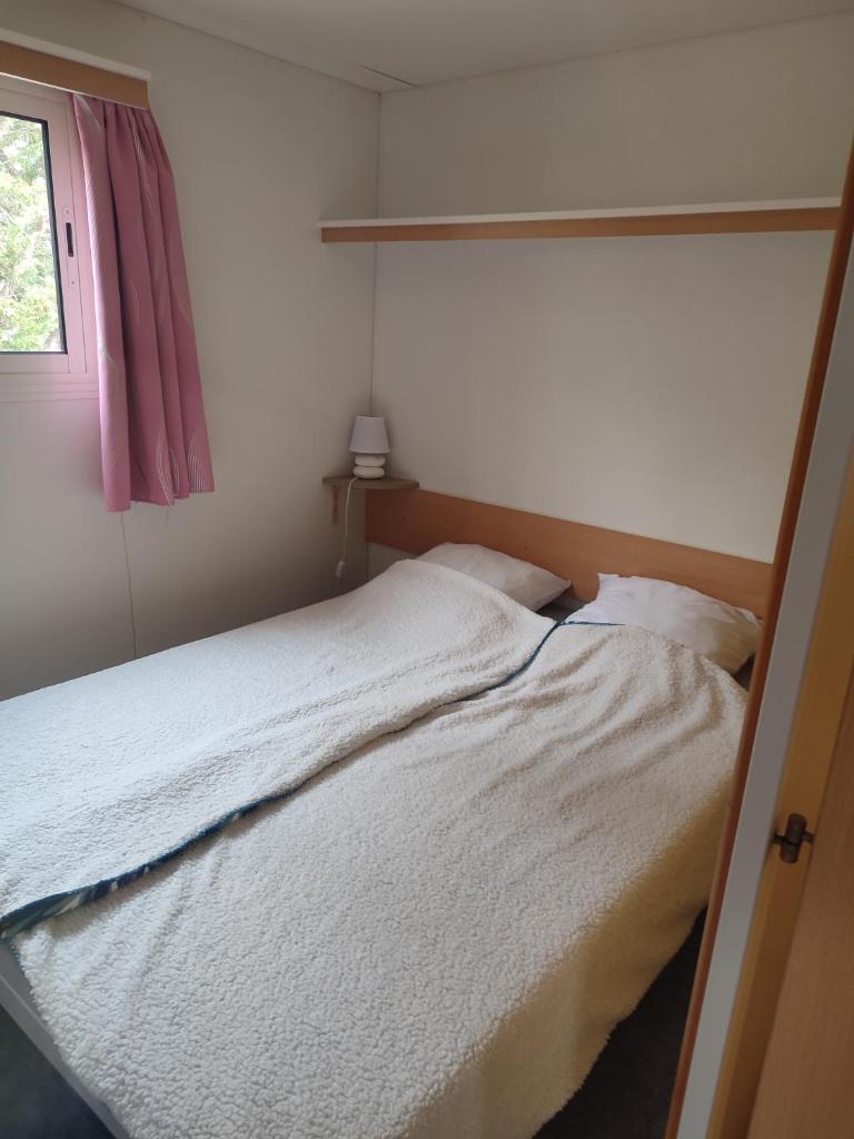 une chambre avec un lit blanc avec une fenêtre dans l'établissement Mobil home a ste croix du verdon camping 3, à Sainte-Croix-de-Verdon