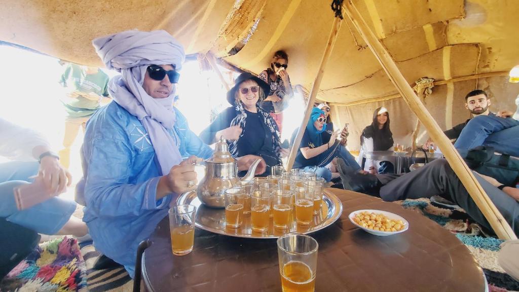 un groupe de personnes assises autour d'une table avec des boissons dans l'établissement Riad Ksar Merzouga, à Merzouga