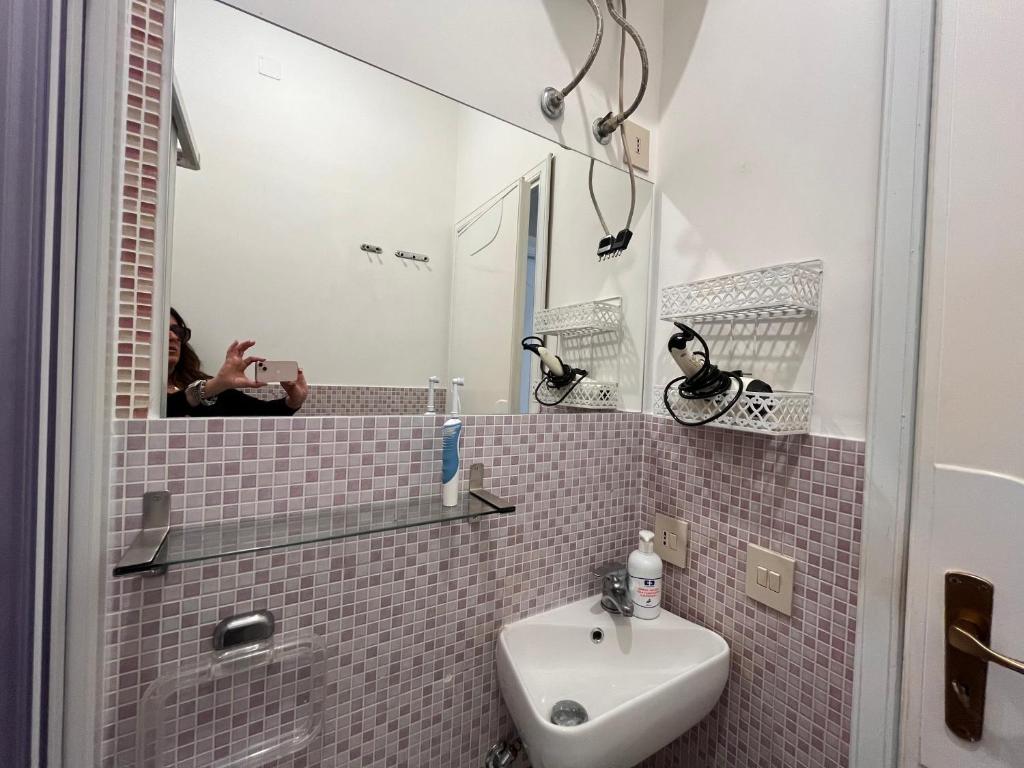 une femme prenant une photo d'une salle de bain avec un lavabo dans l'établissement Ashur mondello, à Palerme