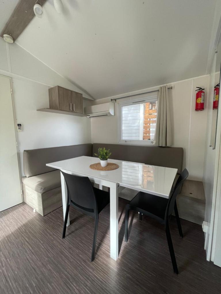 une salle à manger avec une table et des chaises blanches dans l'établissement Mobil Home de Marine, à Port-la-Nouvelle