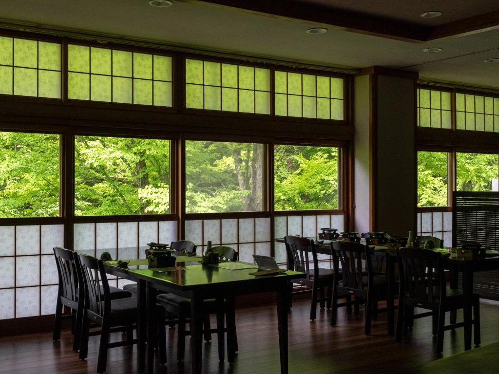 une salle à manger avec tables, chaises et fenêtres dans l'établissement Oyado Tsuruya, à Matsumoto