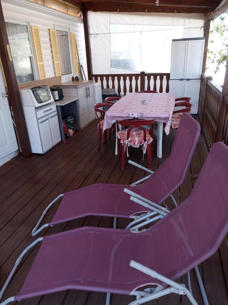 Il dispose d'une terrasse couverte avec des chaises violettes, une table et une cuisine. dans l'établissement Camping l'escale, à Agde