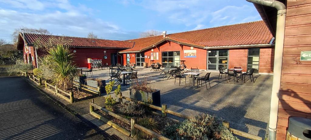 une terrasse extérieure avec tables et chaises devant un bâtiment dans l'établissement Au bonheur des Landes, à Gastes