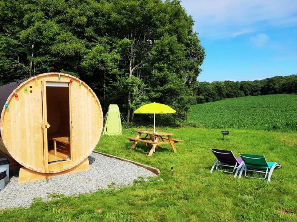 une tente avec des chaises, une table de pique-nique et un parasol dans l'établissement Tonneau bulle insolite, vue sur vignoble, à Pouldergat
