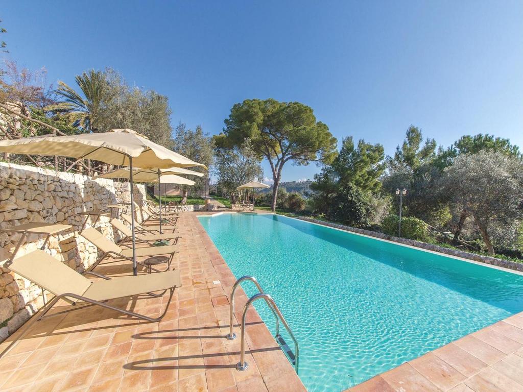 une piscine avec chaises longues et parasols dans l'établissement Baglio Fasana whole property, à Modica